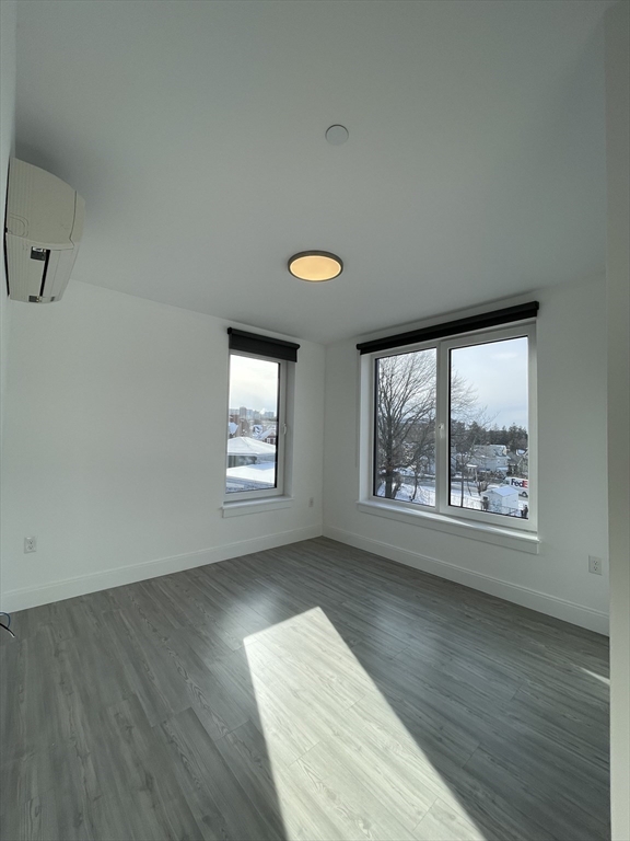42 North Beacon Street, Unit 406 Boston, MA 02134 - Photo 11 of 14 an empty room with wooden floor and windows