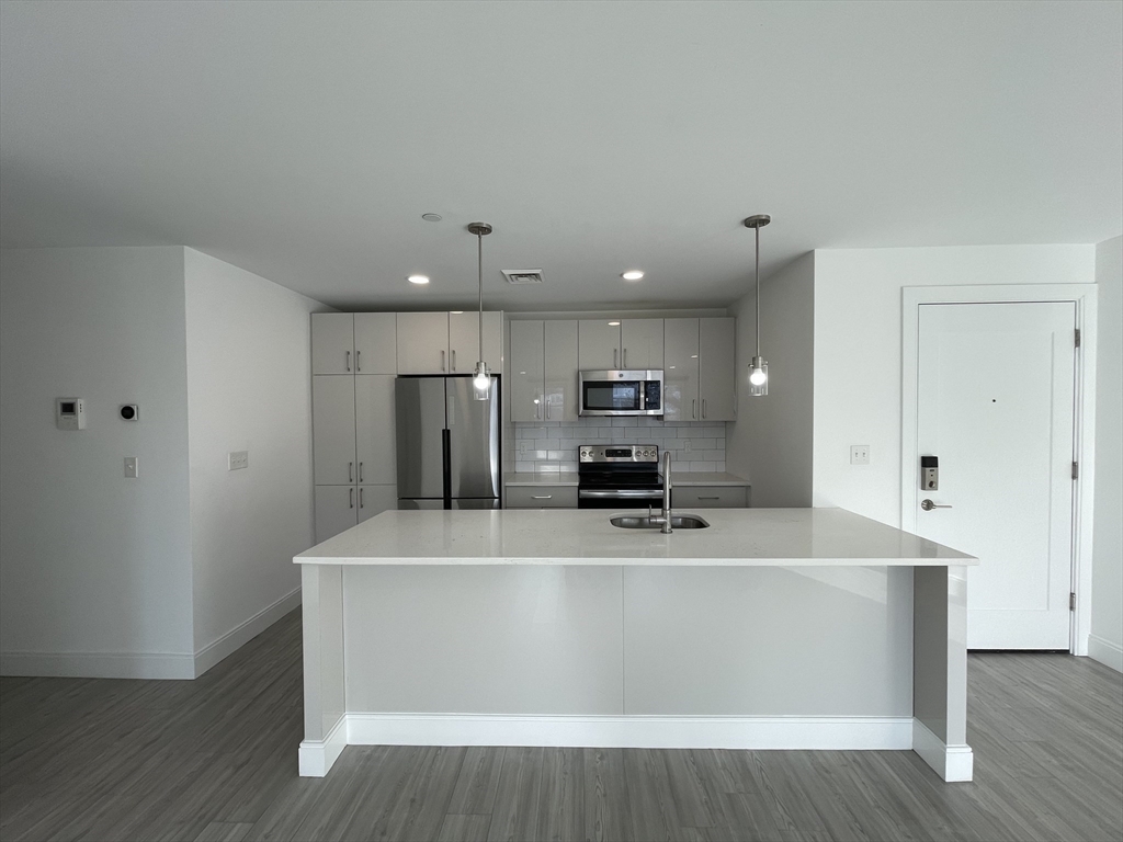 42 North Beacon Street, Unit 406 Boston, MA 02134 - Photo 2 of 14 a view of a kitchen with stainless steel appliances wooden floor and chair
