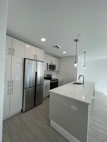 a kitchen with stainless steel appliances granite countertop a refrigerator a sink a stove and a refrigerator