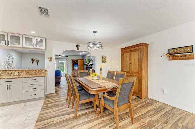 a view of a dining room and livingroom with furniture wooden floor a rug a chandelier