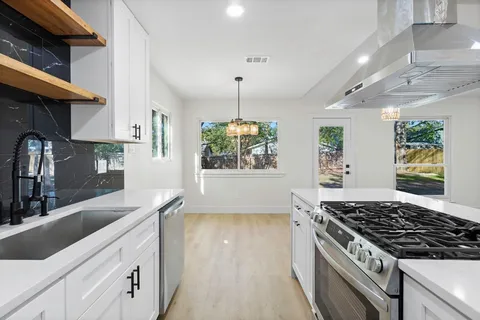 a kitchen with stainless steel appliances granite countertop a sink stove and cabinets