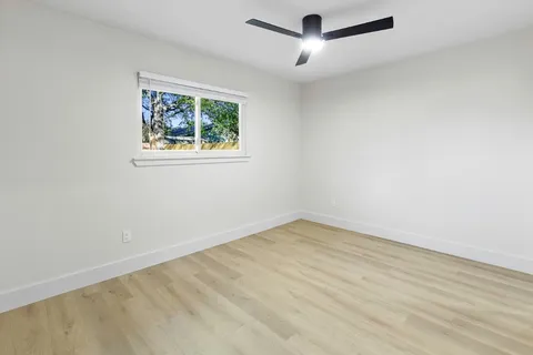 an empty room with a window and ceiling fan