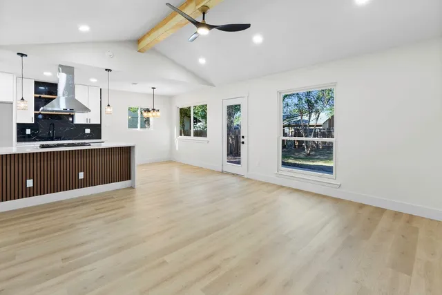 an empty room with kitchen view and a window
