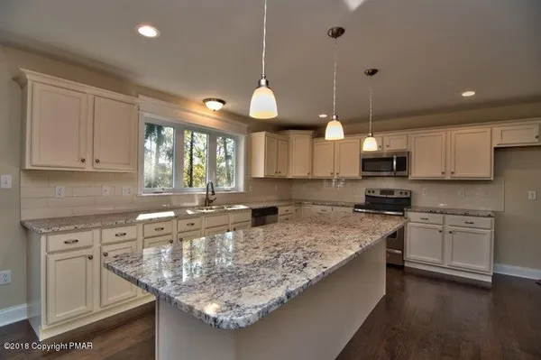 a kitchen with granite countertop a sink a counter space appliances and cabinets