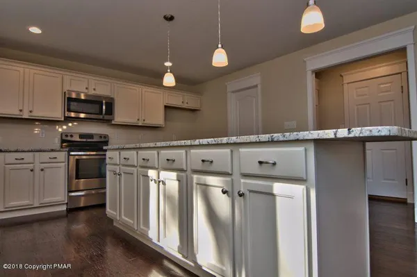 a kitchen with granite countertop white cabinets and a stove top oven