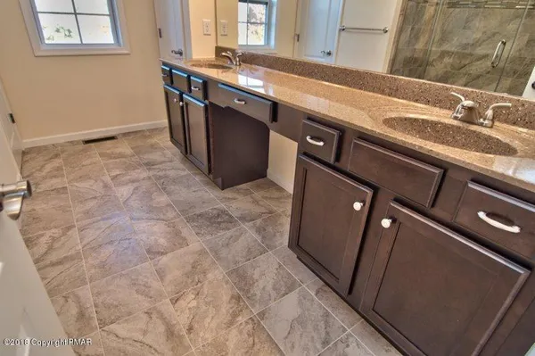 a bathroom with a granite countertop sink a mirror and shower