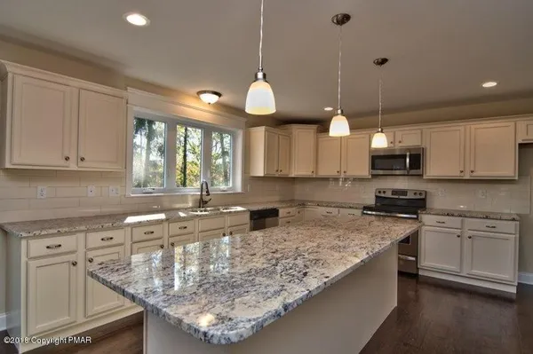 a kitchen with kitchen island granite countertop a stove a sink a center island and cabinets