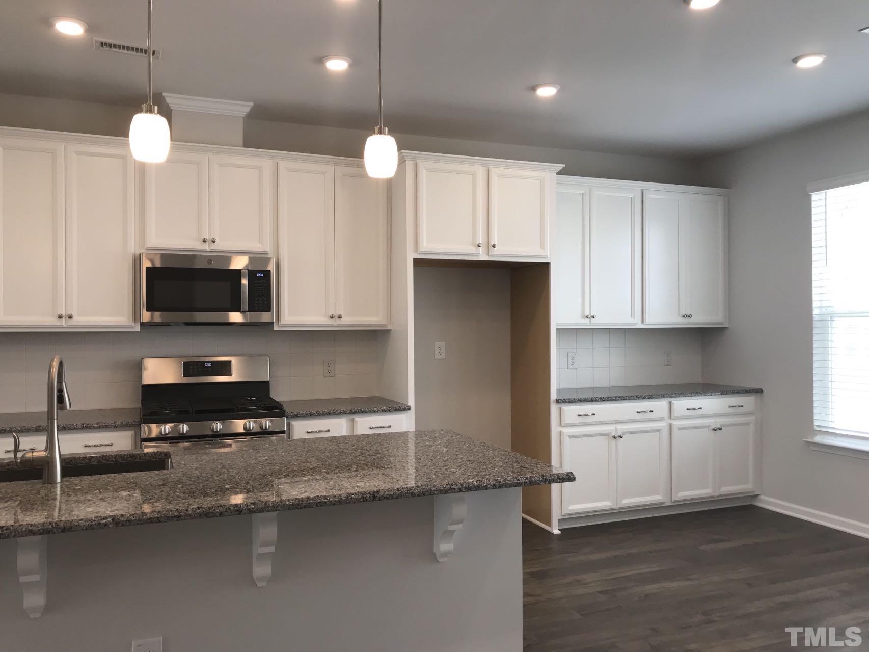1258 Commack Drive Durham, NC 27703 - Photo 48 of 68 a kitchen with granite countertop a stove a sink and a microwave