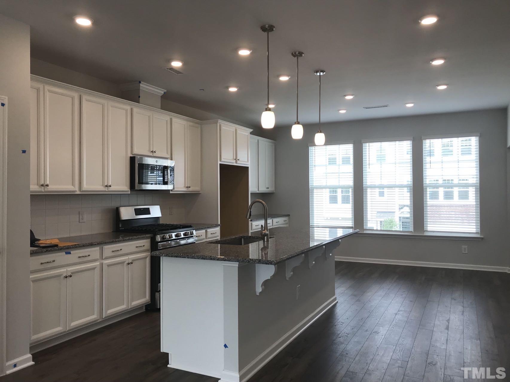 1258 Commack Drive Durham, NC 27703 - Photo 51 of 68 a kitchen with stainless steel appliances granite countertop a refrigerator a sink dishwasher a stove and white cabinets with wooden floor