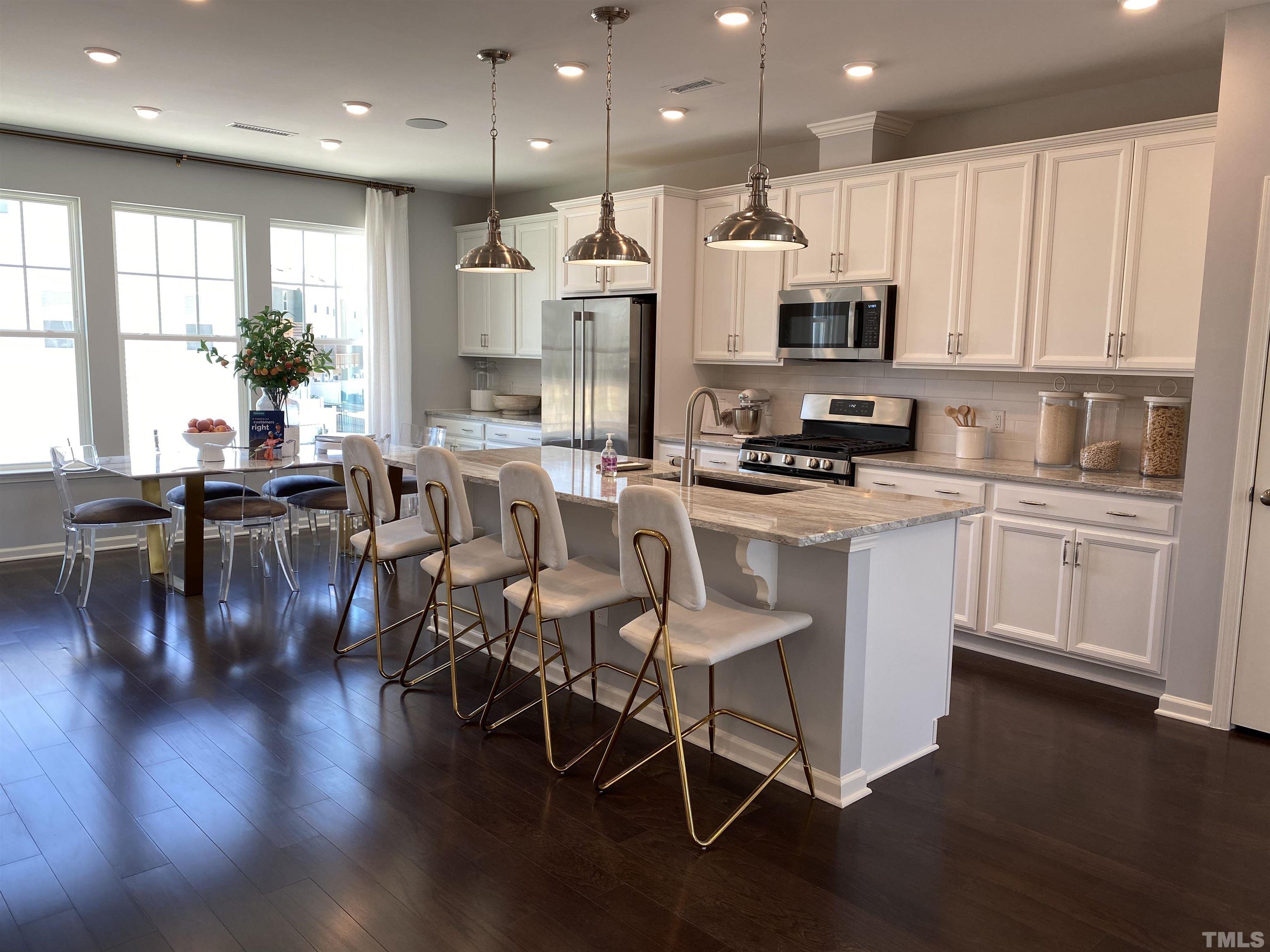 1258 Commack Drive Durham, NC 27703 - Photo 7 of 68 a kitchen with stainless steel appliances kitchen island granite countertop a stove a sink a refrigerator and white cabinets with wooden floor
