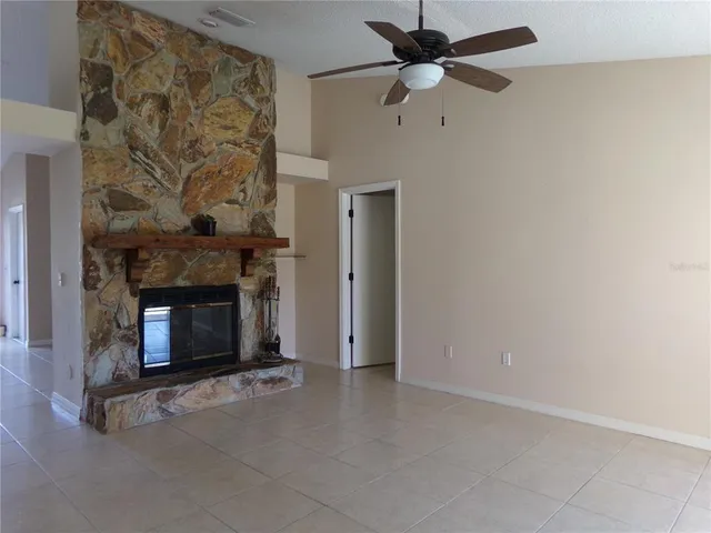 an empty room with a fireplace and a ceiling fan