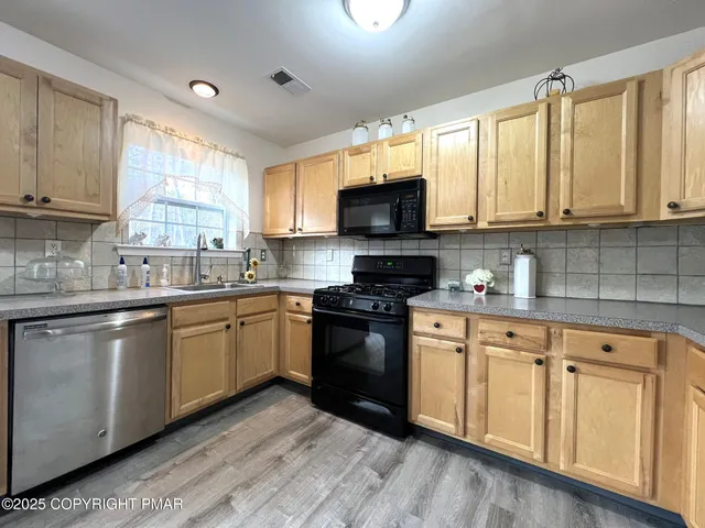 a kitchen with stainless steel appliances granite countertop a sink a stove cabinets and a window