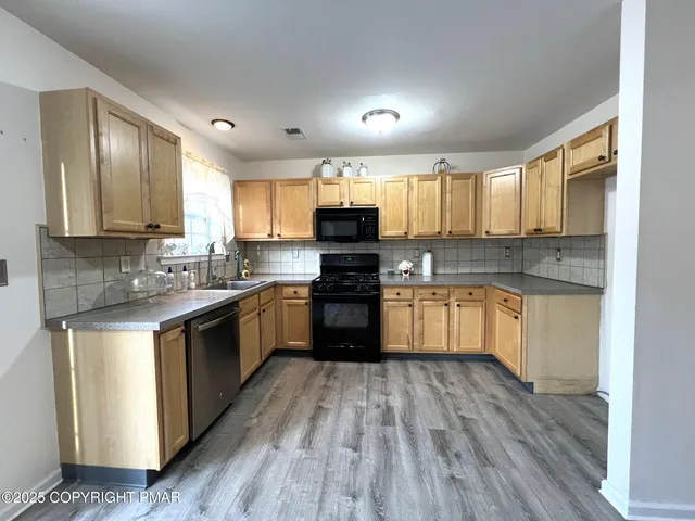 a kitchen with granite countertop wooden floors stainless steel appliances and window