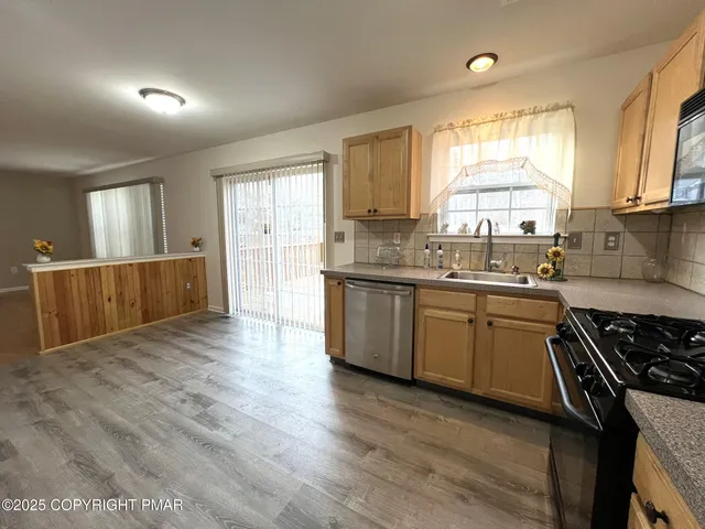 a kitchen with stainless steel appliances granite countertop a sink a stove cabinets counter space and a window