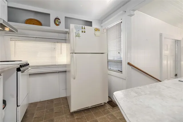 a white refrigerator freezer and a stove sitting inside of a kitchen