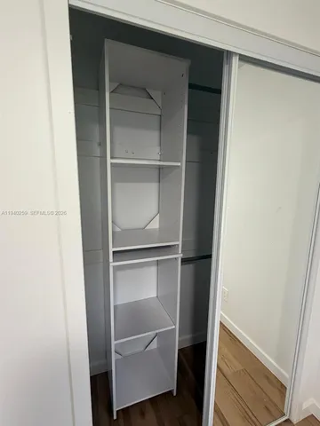 a walk in closet with wooden floor