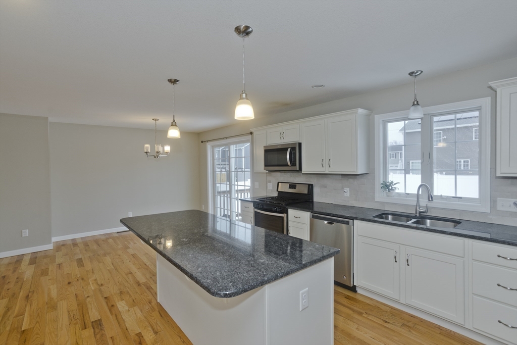 239 Gresham Street Springfield, MA 01119 - Photo 11 of 39 a kitchen with stainless steel appliances granite countertop a sink dishwasher and white cabinets with wooden floor