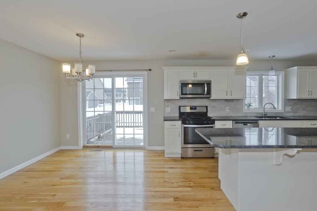239 Gresham Street Springfield, MA 01119 - Photo 13 of 39 a kitchen with stainless steel appliances granite countertop a stove top oven a sink dishwasher a dining table and chairs with wooden floor