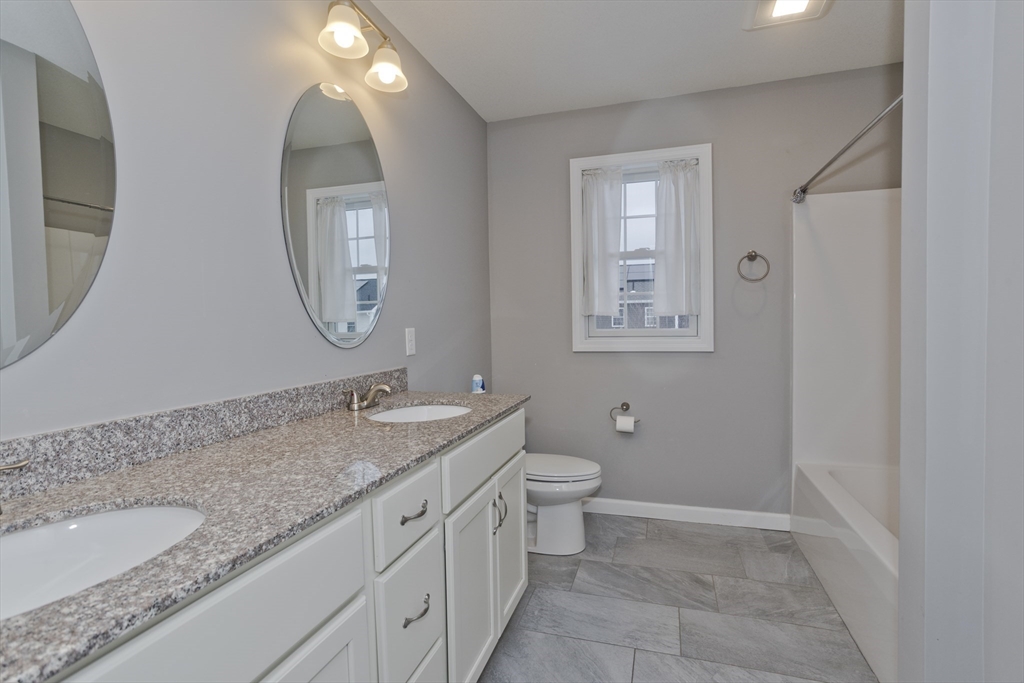 239 Gresham Street Springfield, MA 01119 - Photo 25 of 39 a bathroom with a granite countertop sink mirror vanity and toilet