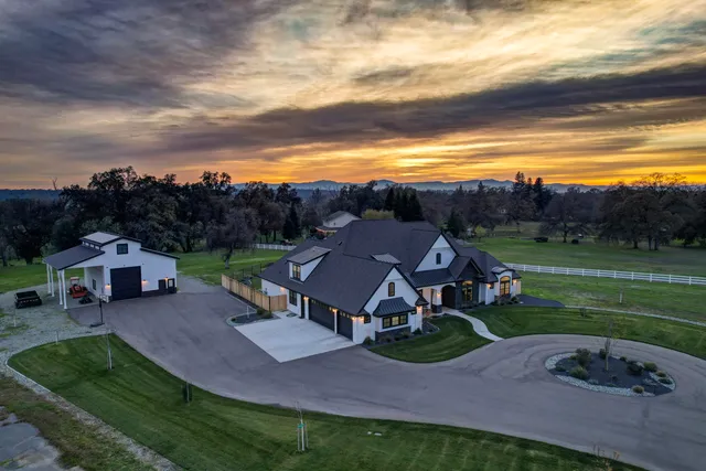 a kitchen with stainless steel appliances granite countertop a stove a refrigerator a sink a dining table and chairs with wooden floor