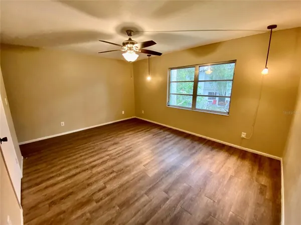 a view of an empty room with wooden floor and a window