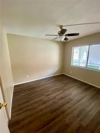 an empty room with wooden floor fan and windows
