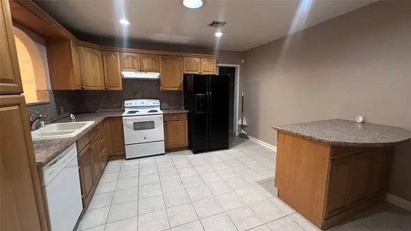 a kitchen with stainless steel appliances granite countertop a stove a sink and a refrigerator
