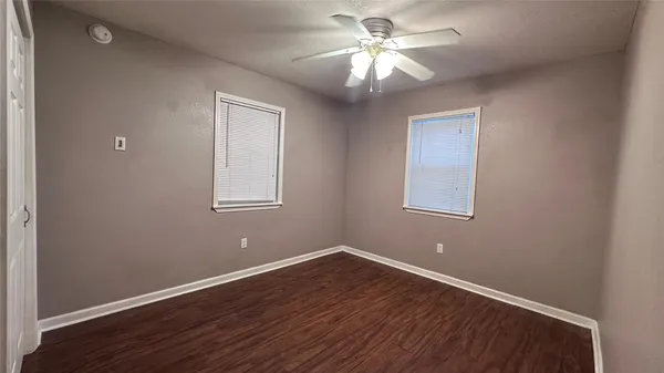 a view of a big room with wooden floor and windows