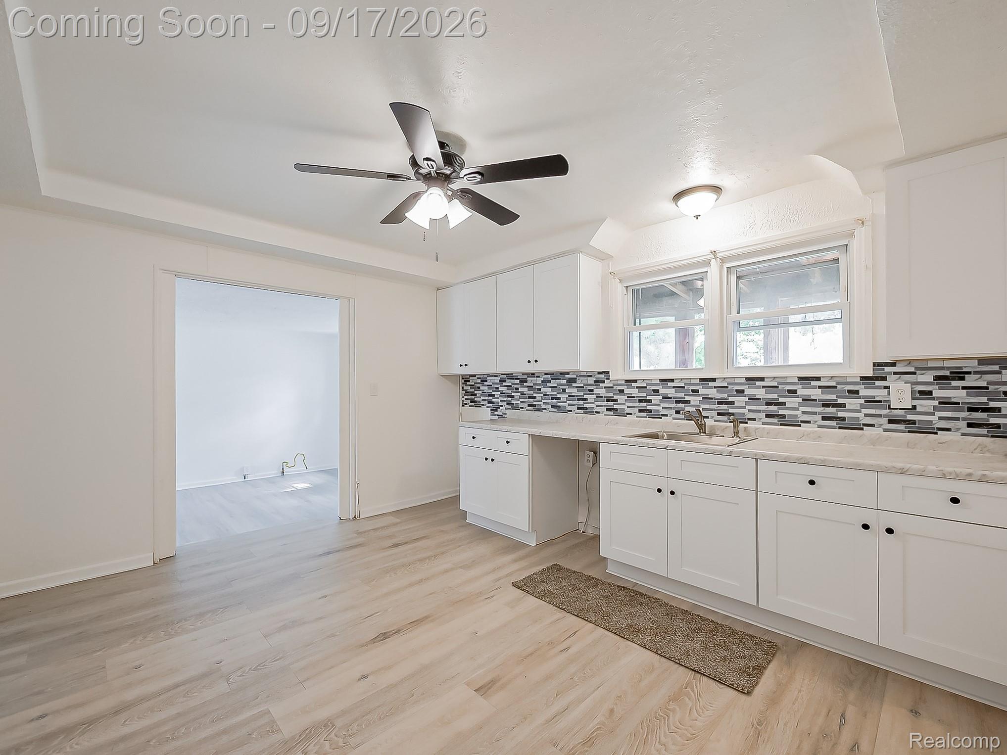 14102 Toepfer Road Warren, MI 48089 - Photo 4 of 39 Kitchen featuring white cabinetry, light-toned countertops, a mosaic tile backsplash, and wood-finish flooring