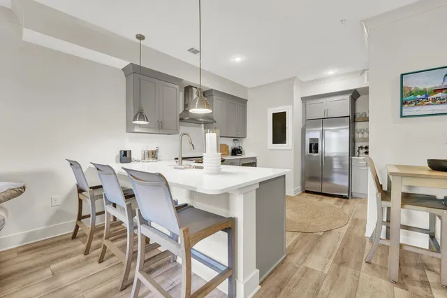 a kitchen with stainless steel appliances kitchen island granite countertop a dining table chairs refrigerator and sink