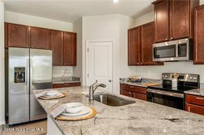 Undisclosed Address Vero Beach, FL 32967 - Photo 7 of 36 a kitchen with stainless steel appliances wooden cabinets a stove a sink and a microwave