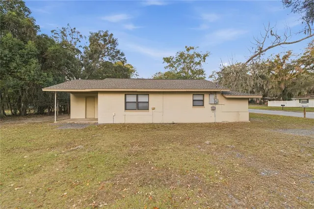 a front view of house with yard and trees in the background