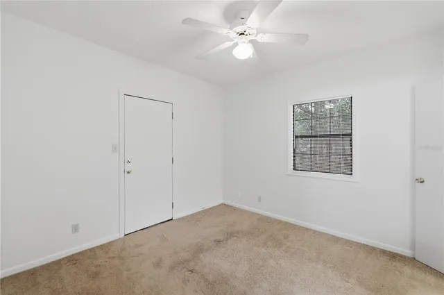an empty room with a fan & a window