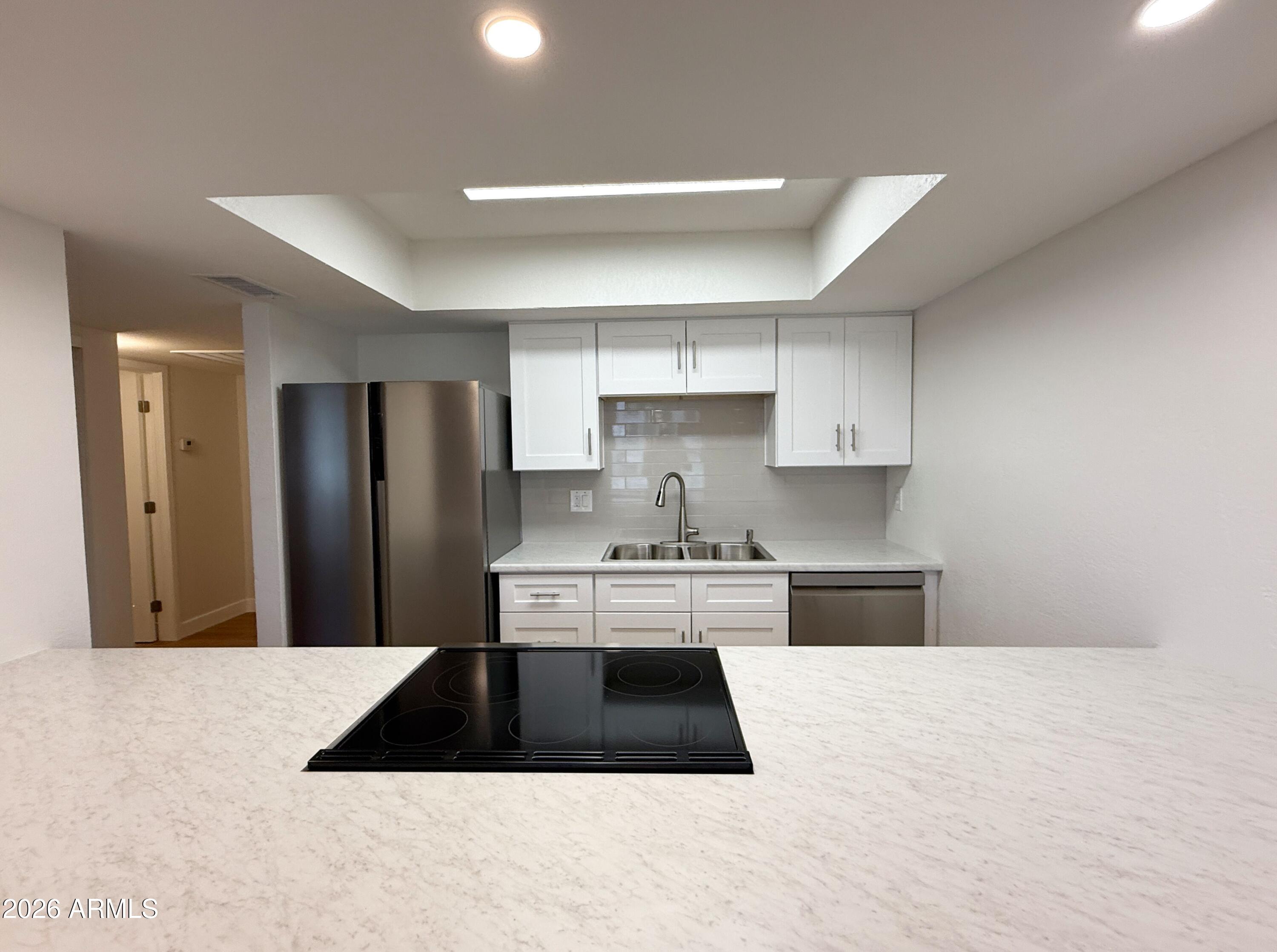 18202 North Cave Creek Road, Unit 148 Phoenix, AZ 85032 - Photo 9 of 19 a kitchen with a refrigerator and white cabinets