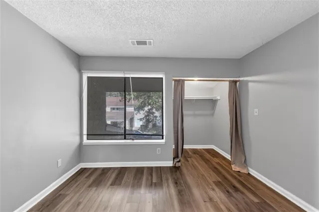 an empty room with wooden floor and windows