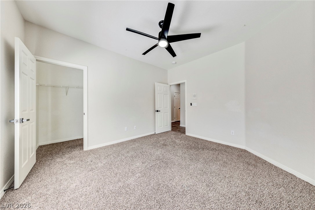 740 Aldo Rae Court, Unit NONE Henderson, NV 89052 - Photo 22 of 35 A spacious bedroom features plush carpeting and a modern ceiling fan, offering comfortable living.