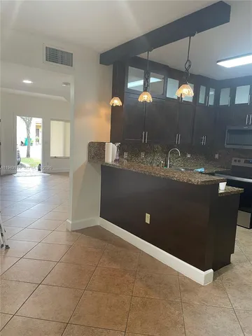 a living room with granite countertop kitchen island a sink and a stove