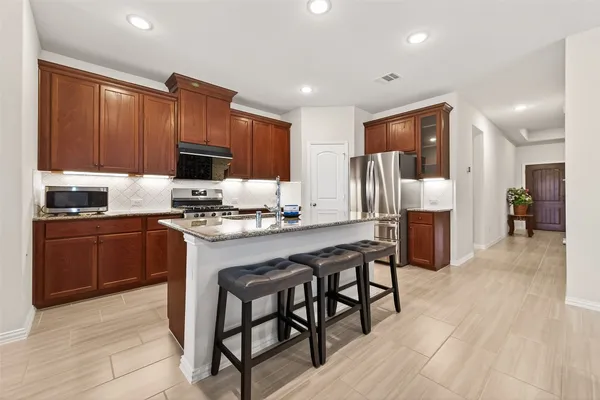 a kitchen with granite countertop wooden cabinets a refrigerator a stove a sink and a oven