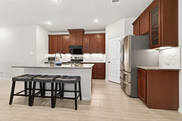 a kitchen with kitchen island granite countertop a sink cabinets and stainless steel appliances