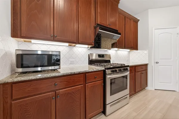 a kitchen with stainless steel appliances granite countertop a stove microwave and sink