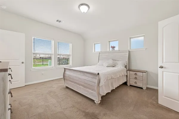 a spacious bedroom with a bed and a flat screen tv