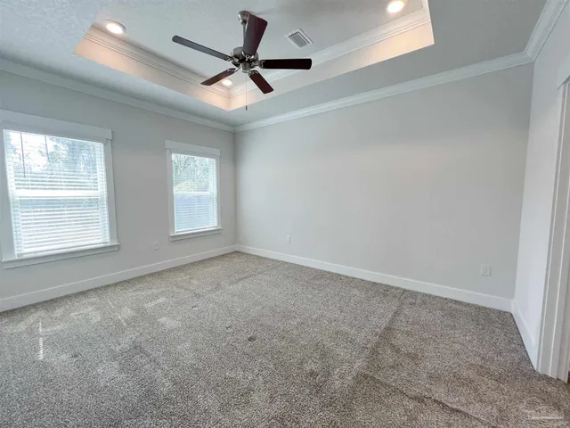 an empty room with ceiling fan and windows
