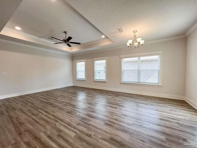 an empty room with wooden floor a ceiling fan and windows