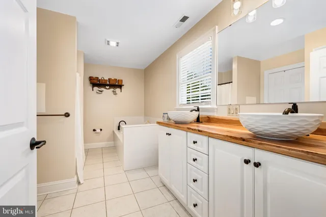 a spacious bathroom with a granite countertop sink a mirror and a bathtub