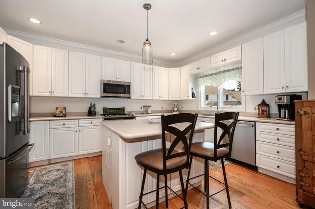 a kitchen with stainless steel appliances kitchen island granite countertop a table chairs microwave and sink