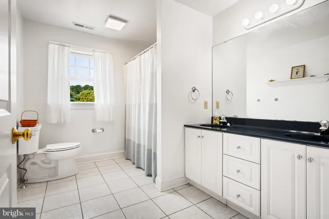 a bathroom with a granite countertop sink a toilet a mirror and shower