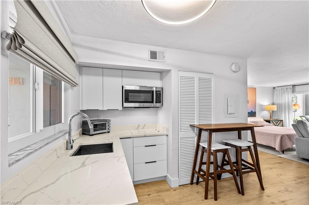 377 Vanderbilt Beach Road, Unit 102 Naples, FL 34108 - Photo 5 of 19 a kitchen with stainless steel appliances kitchen island granite countertop a sink and cabinets