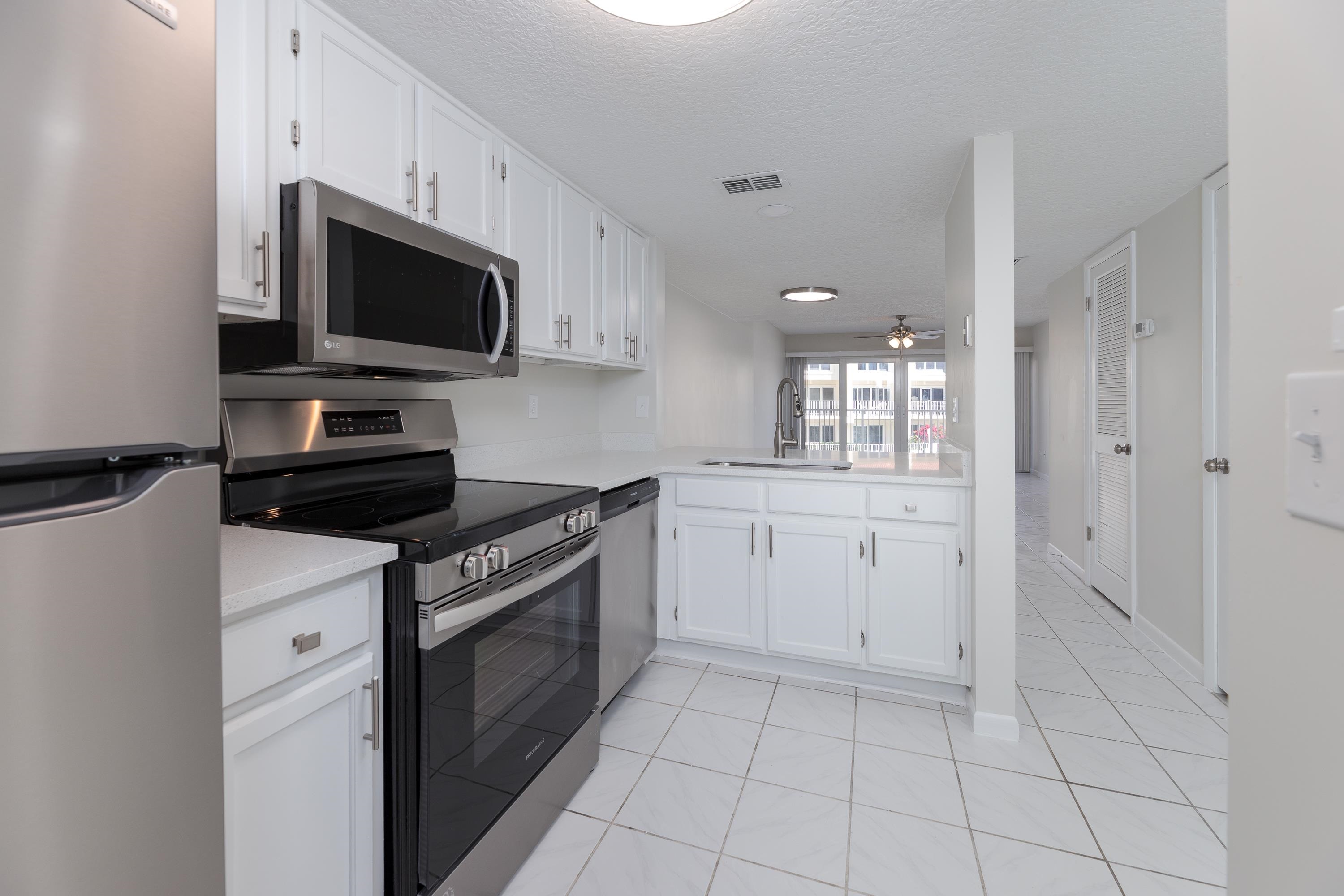 390 A1A Beach Boulevard, Unit 48 St. Augustine, FL 32080 - Photo 4 of 24 a kitchen with white cabinets and appliances