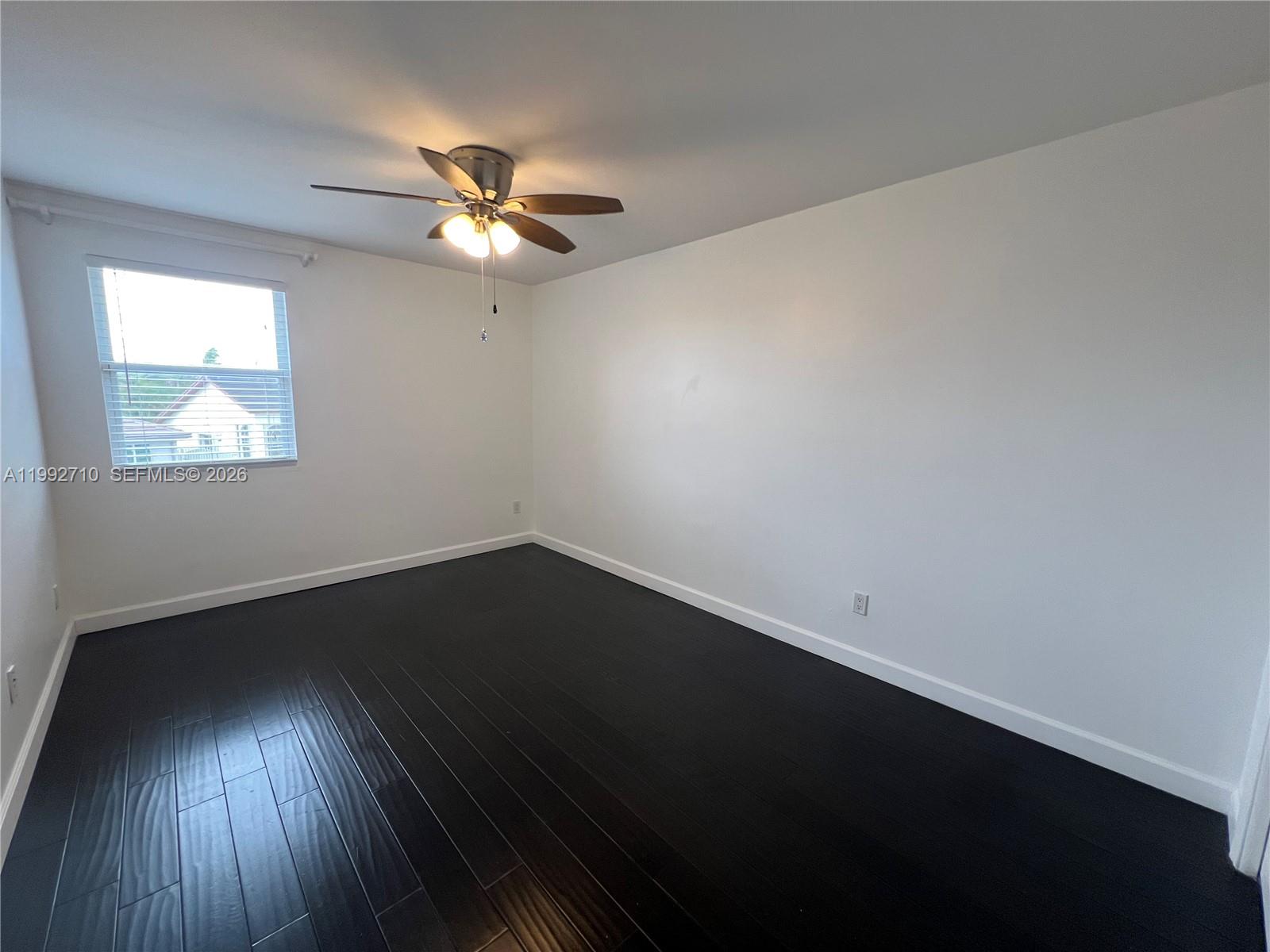 15511 Southwest 59th Street Miami, FL 33193 - Photo 21 of 34 an empty room with wooden floor fan and windows