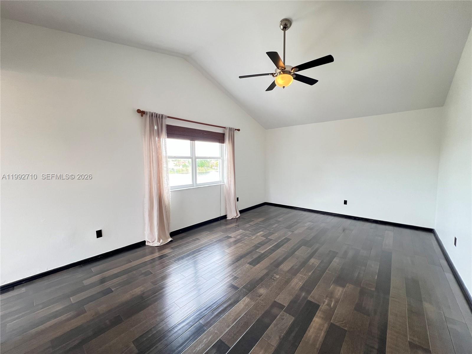 15511 Southwest 59th Street Miami, FL 33193 - Photo 6 of 34 an empty room with wooden floor ceiling fan and windows
